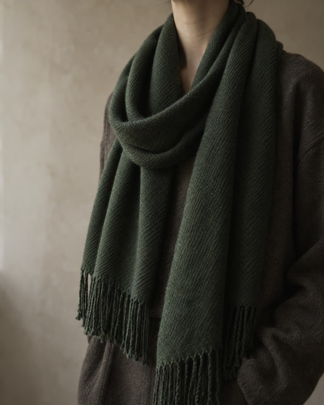 A softly draped forest green cashmere scarf with hand-tied fringe